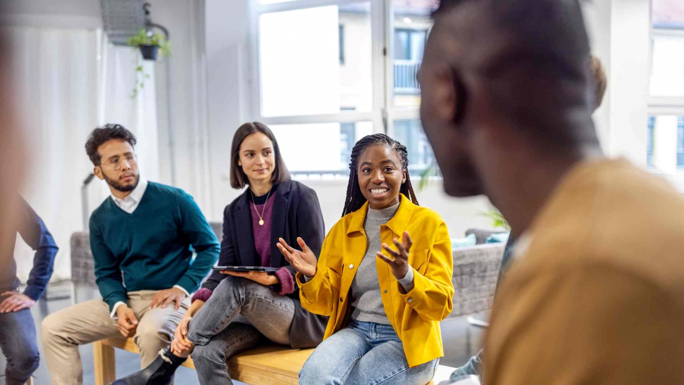 African woman talking with colleagues sitting in circle at a coworking office