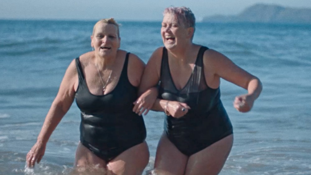 Two women from the Bluetits Cold Water Swimming Club in the sea wearing black bathing suits