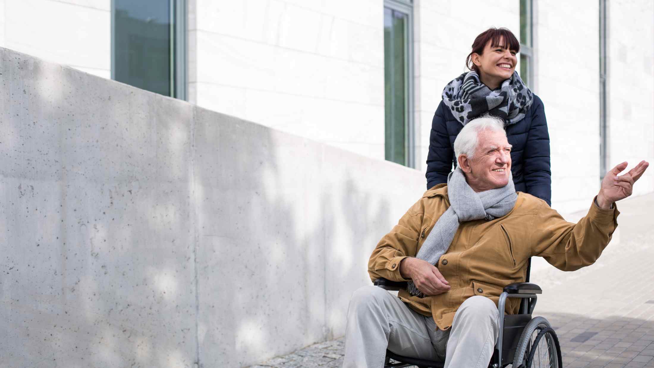 Disabled senior man being pushed in his wheelchair by a woman