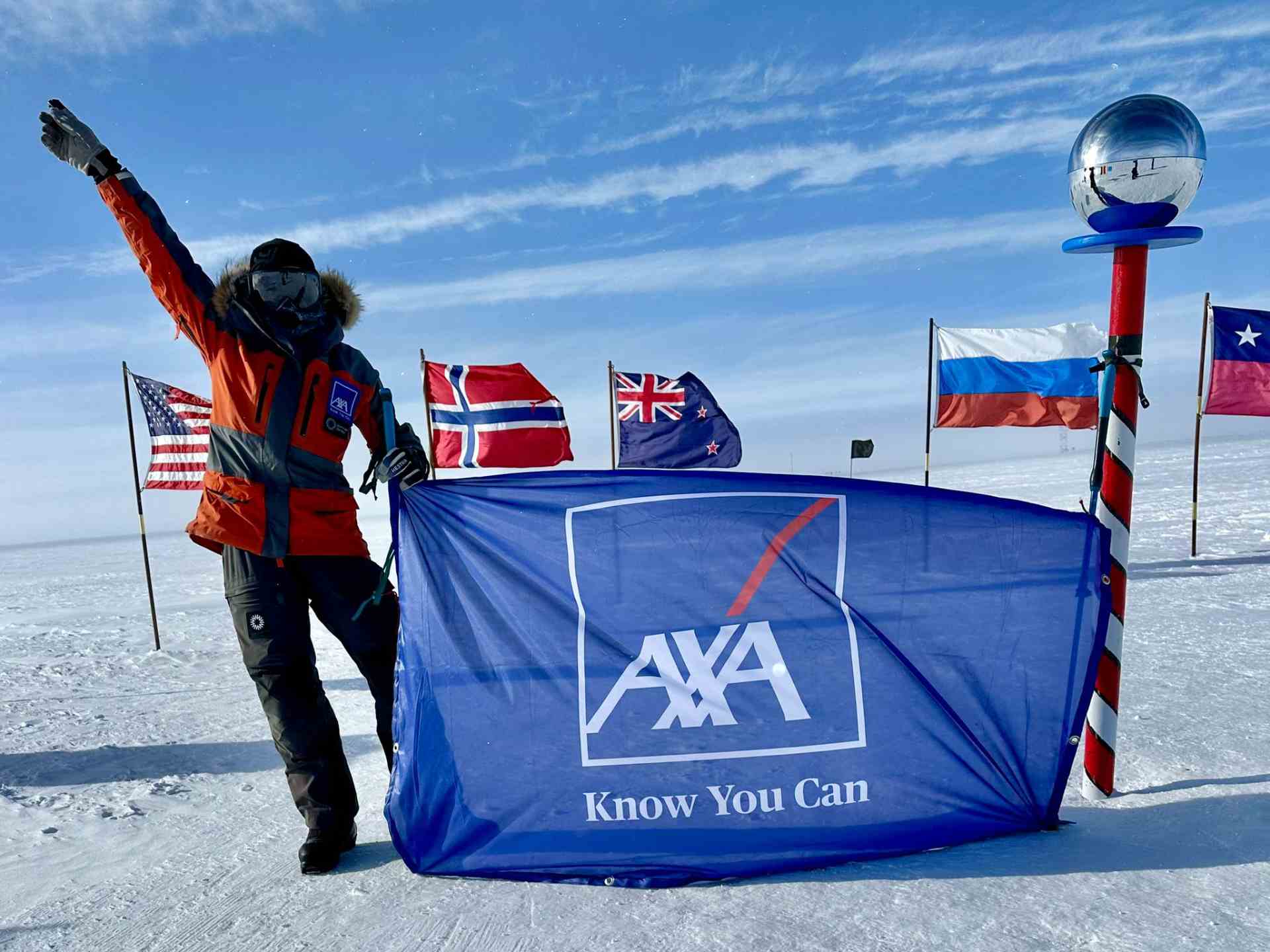 Car Burford the Molar Explorer at the North Pole holding an AXA Know You Can flag
