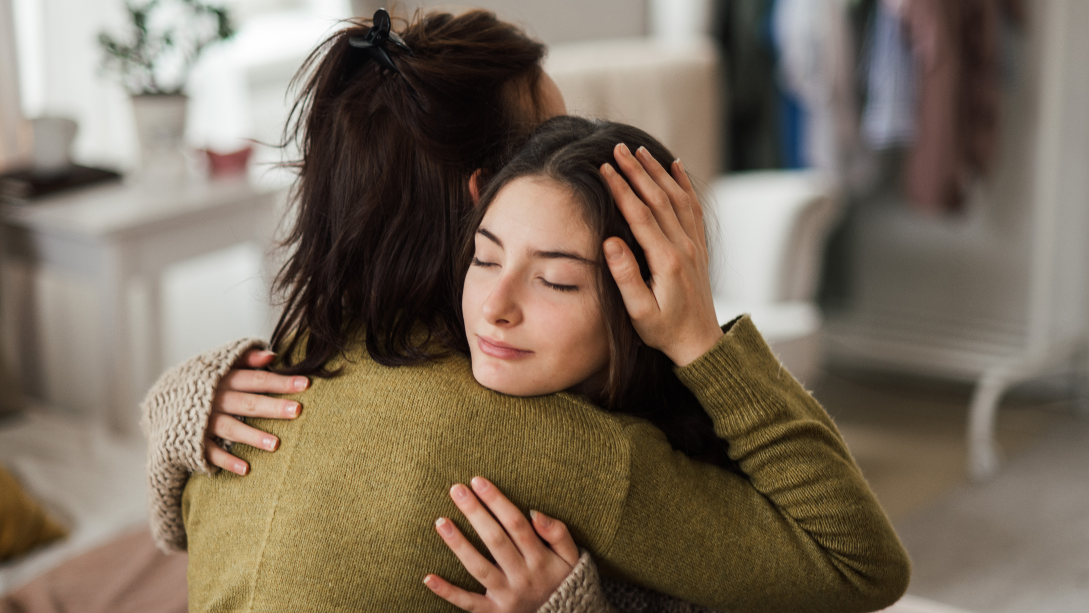 Two women are embracing in a warm, supportive hug