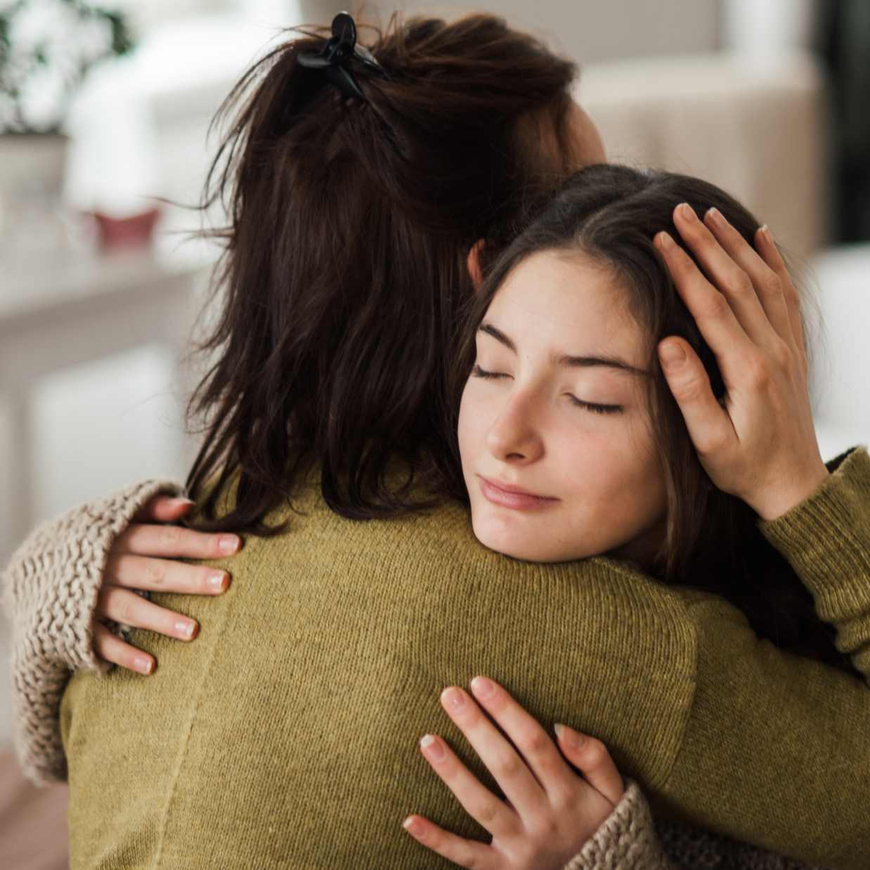 Two women are embracing in a warm, supportive hug