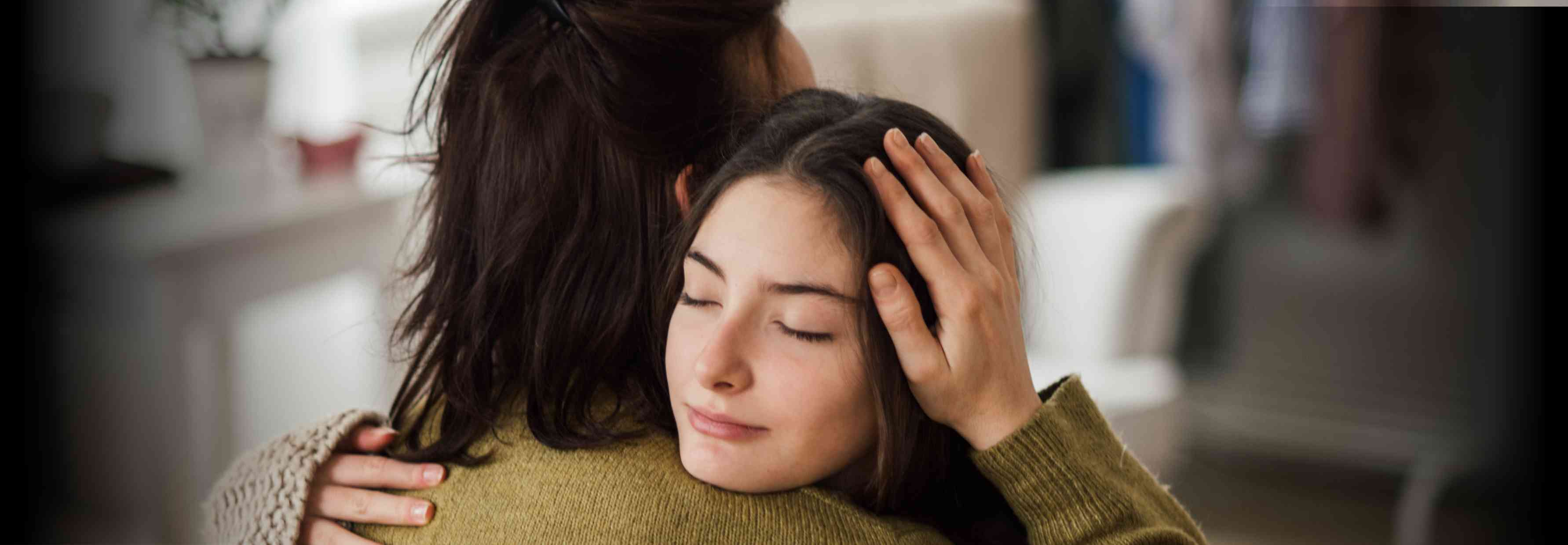 Two women are embracing in a warm, supportive hug