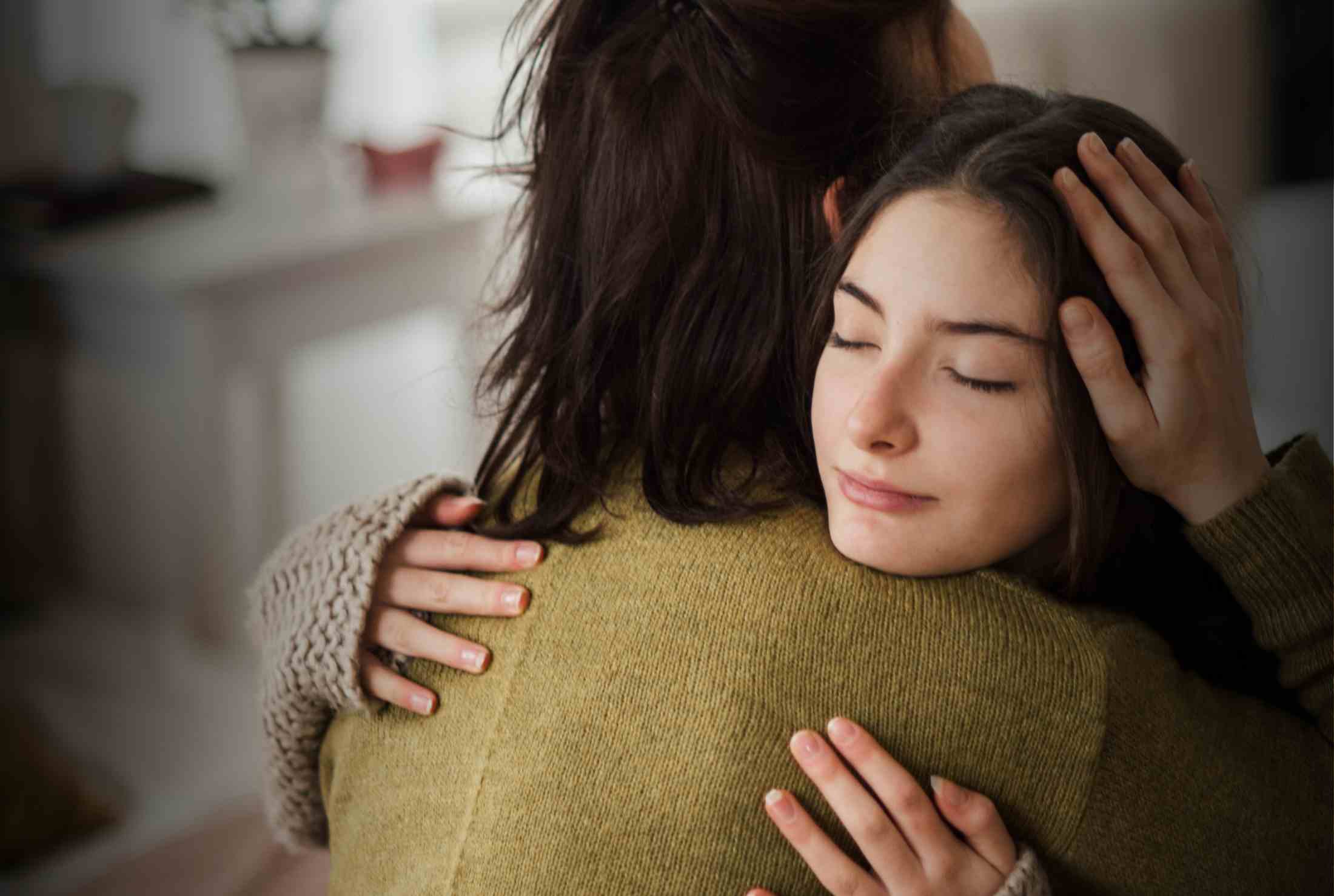Two women are embracing in a warm, supportive hug