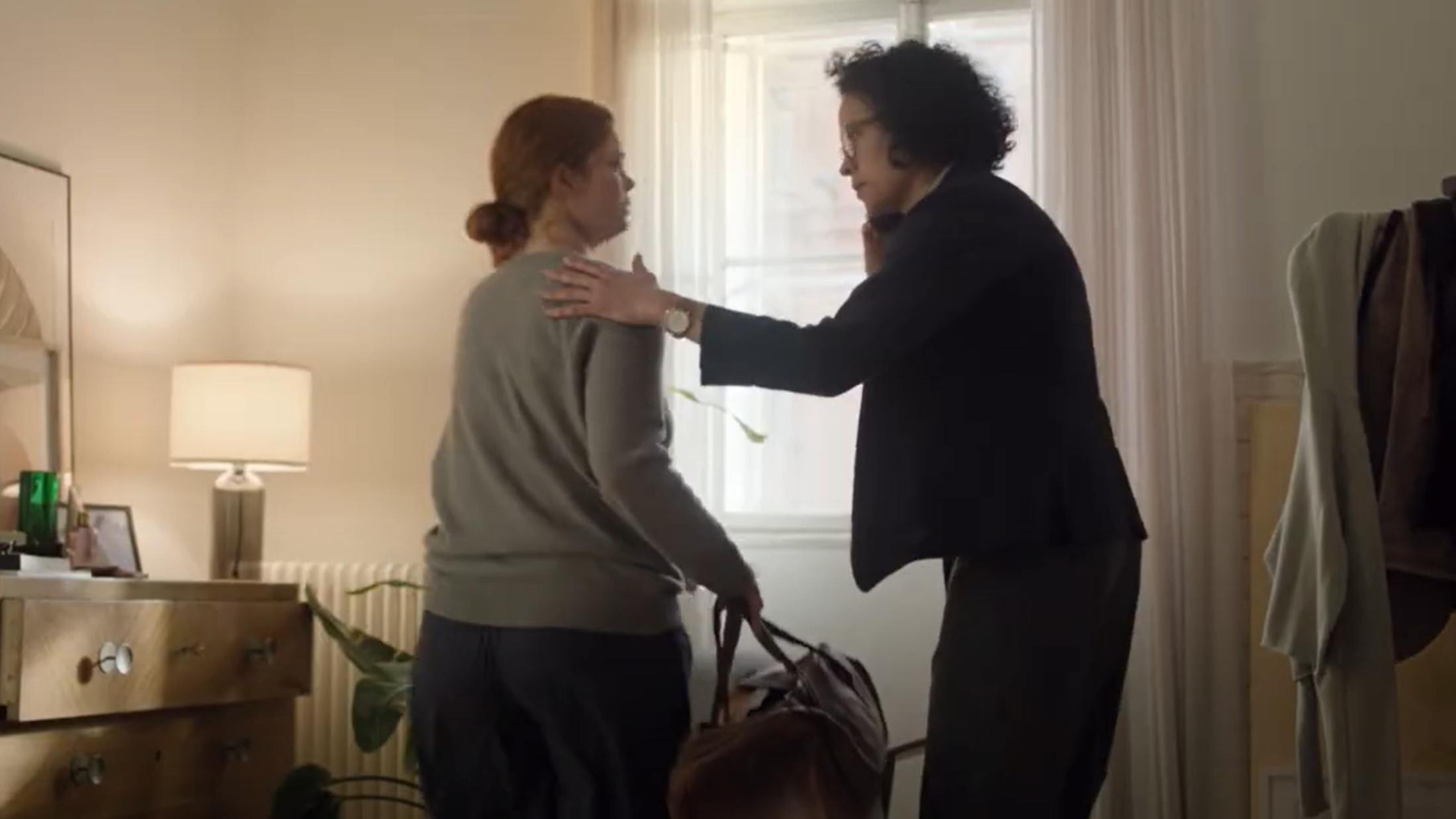A woman escaping domestic abuse with her luggage is being supported by another woman