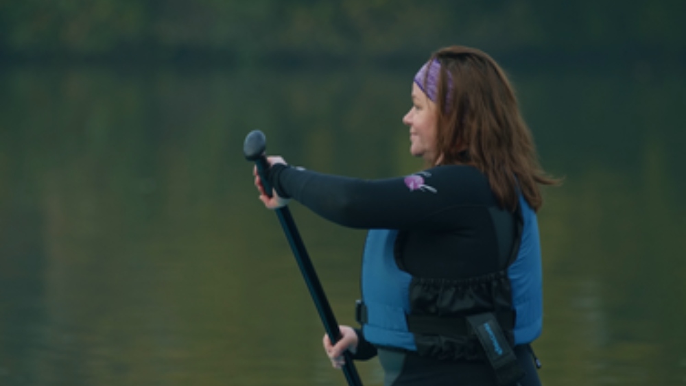 Woman wearing a blue life jacket with paddle in her hand