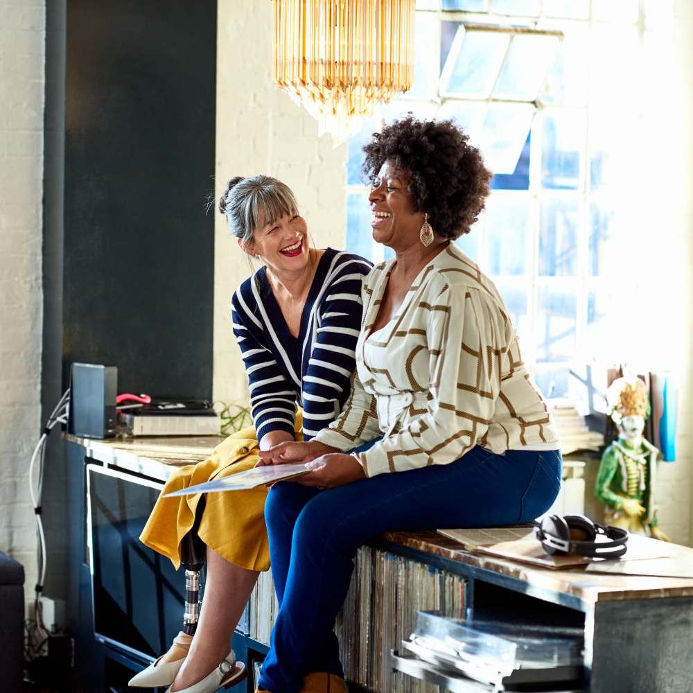 Mature women laughing together in stylish loft apartment teaser