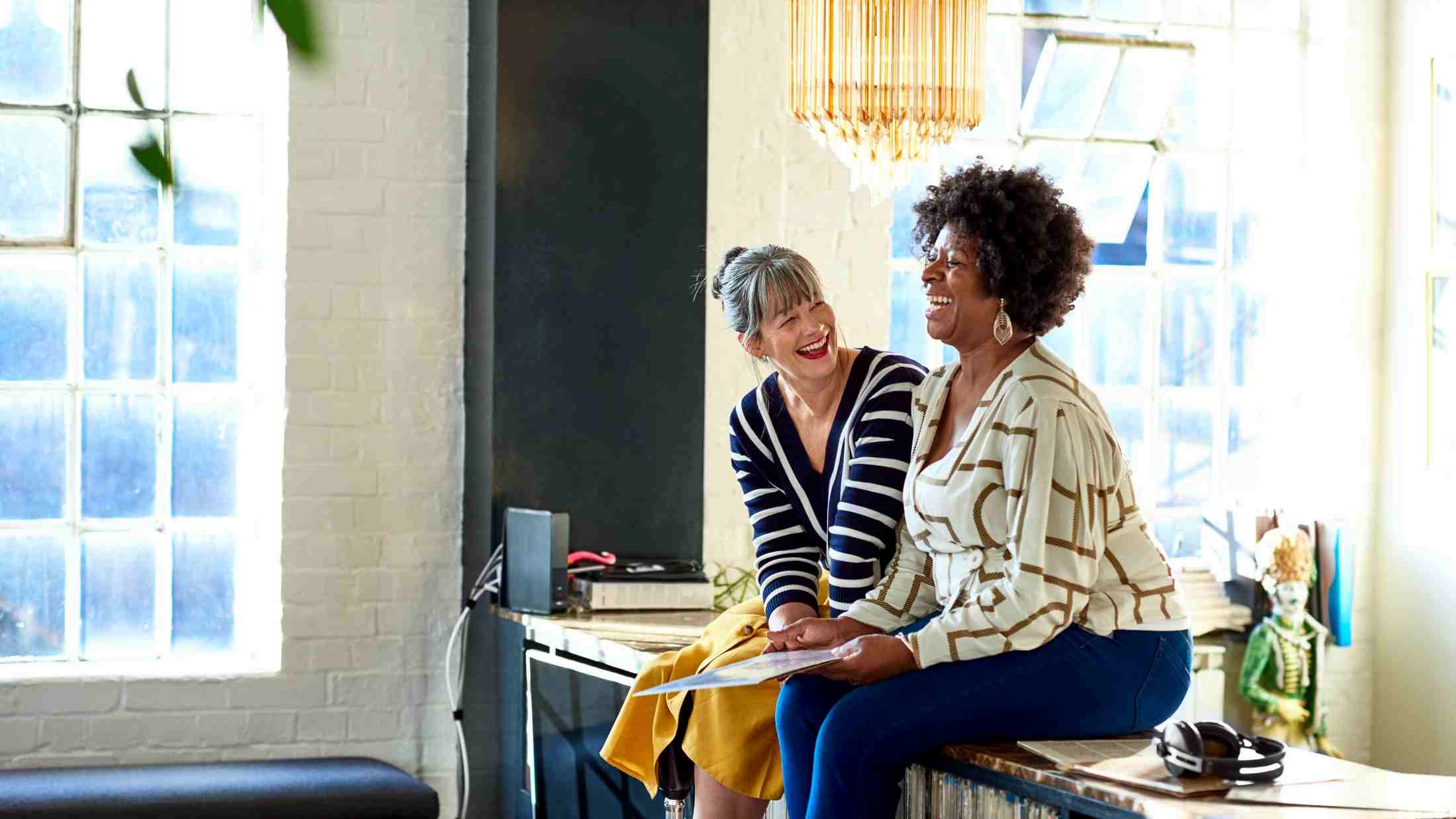 Mature women laughing together in stylish loft apartment