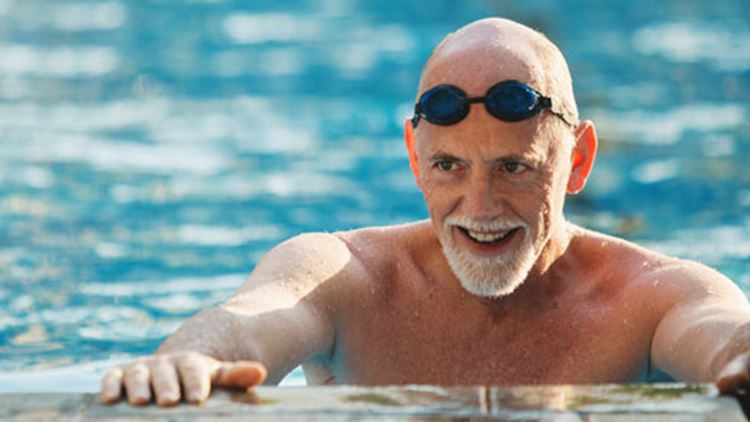 An old man swimming in a swimming pool