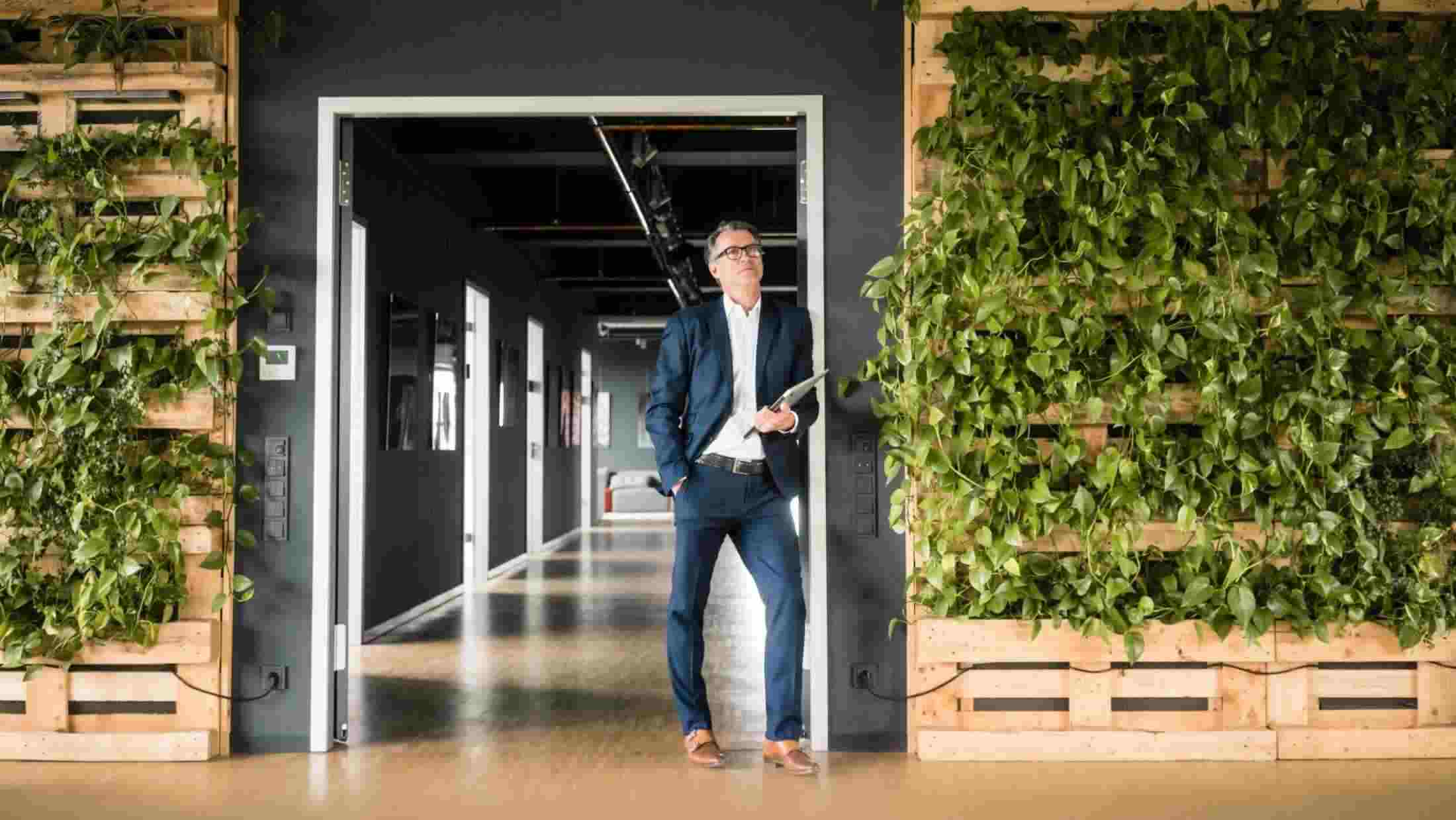 Mature businessman with laptop standing in green office