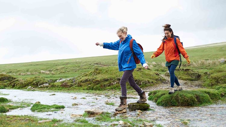 Two hikers crossing stream in countryside