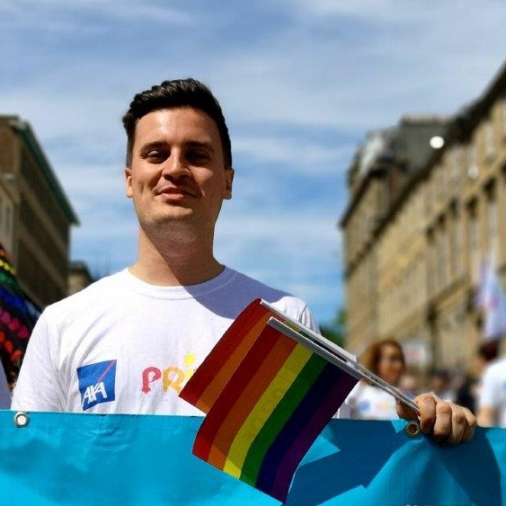 AXA employee at Pride event holding rainbow flags