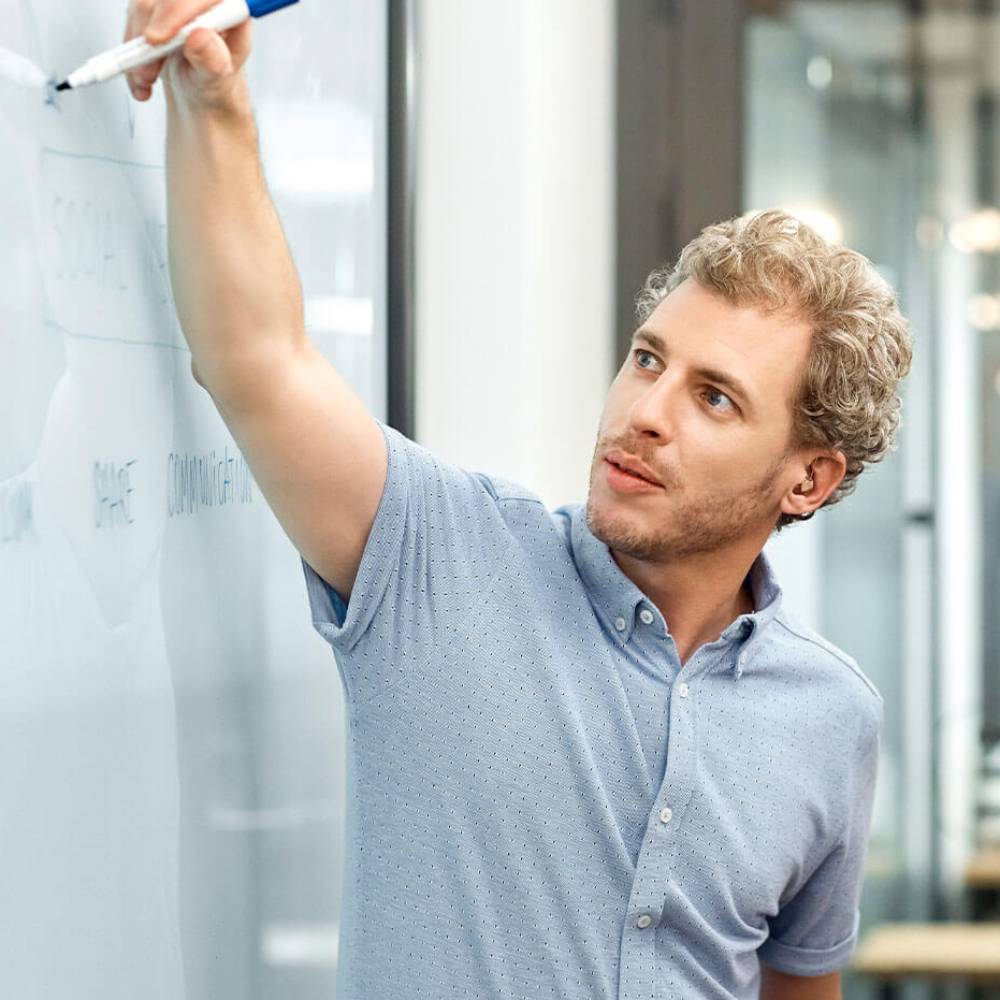 Man with blue pen writing on whiteboard