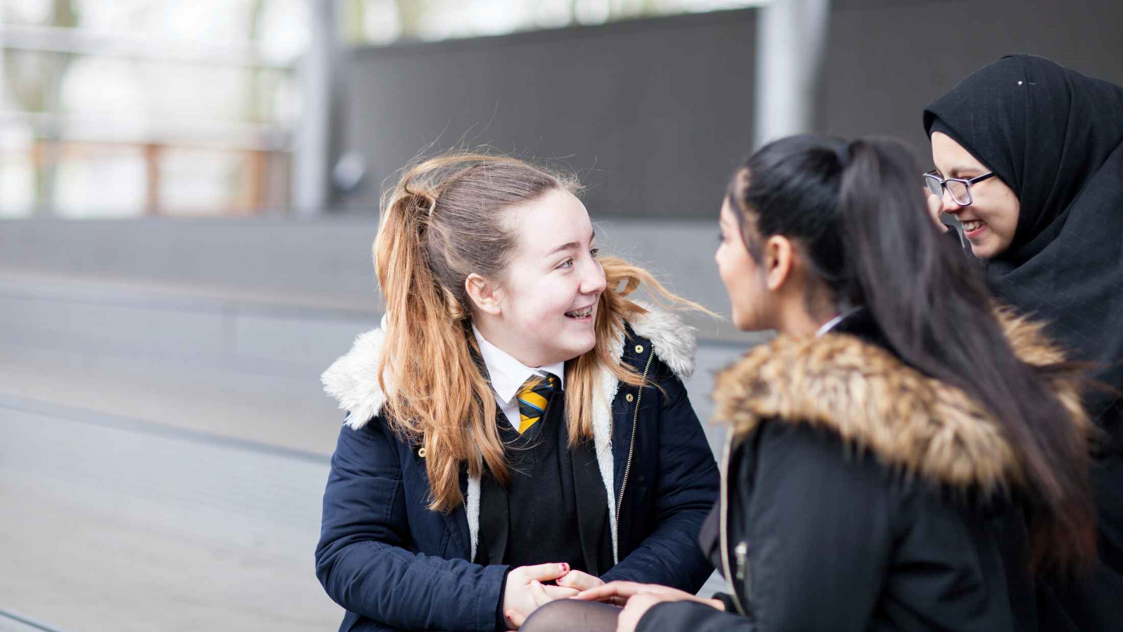 Three female high school students taking a break with smile in school