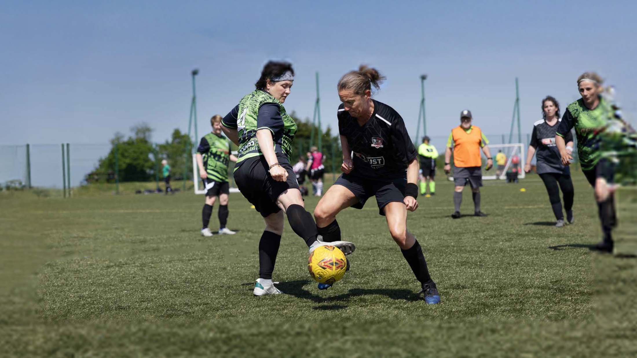 Two women's walking football players compete for the ball