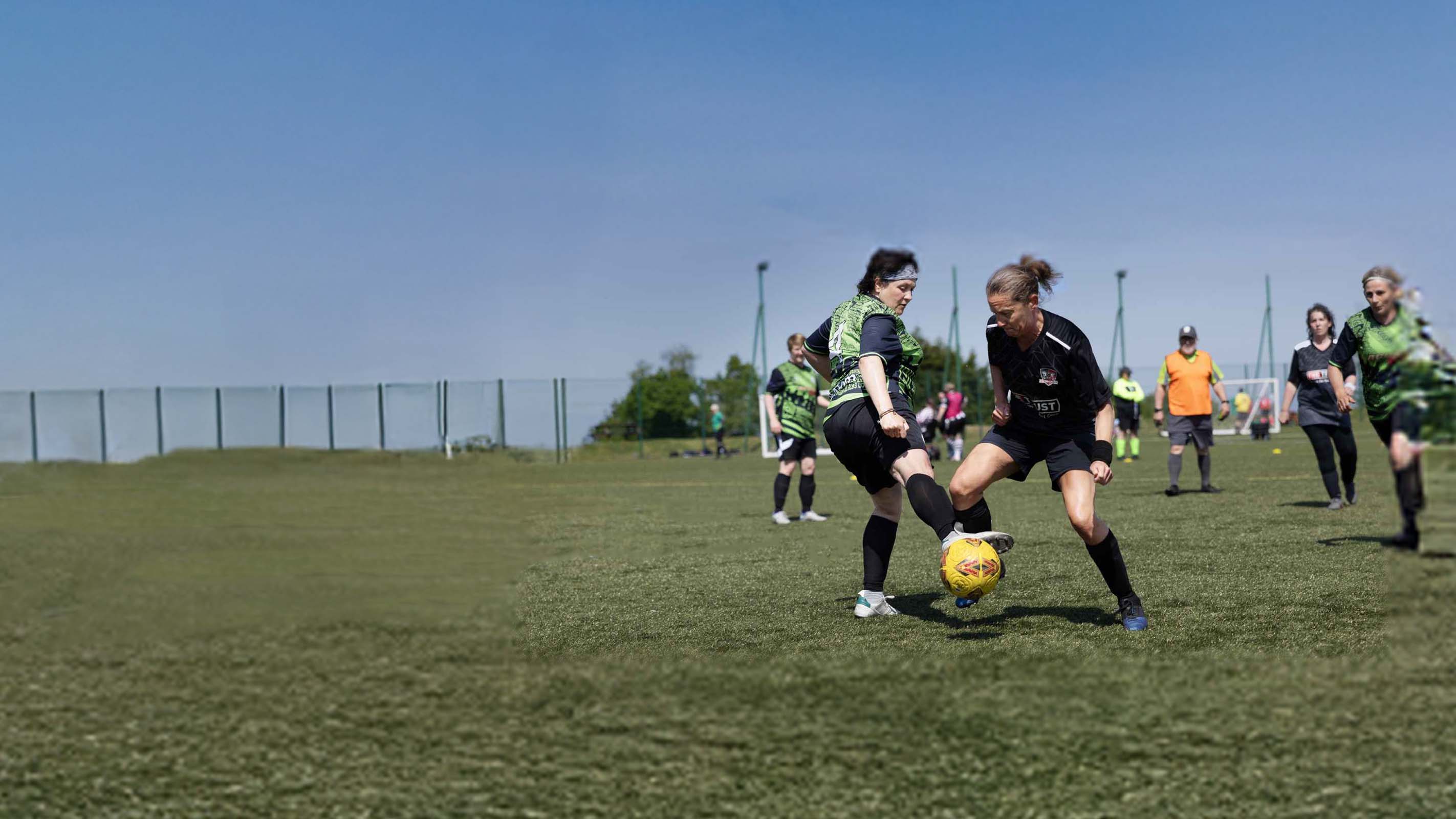 Two women's walking football players competing for the ball