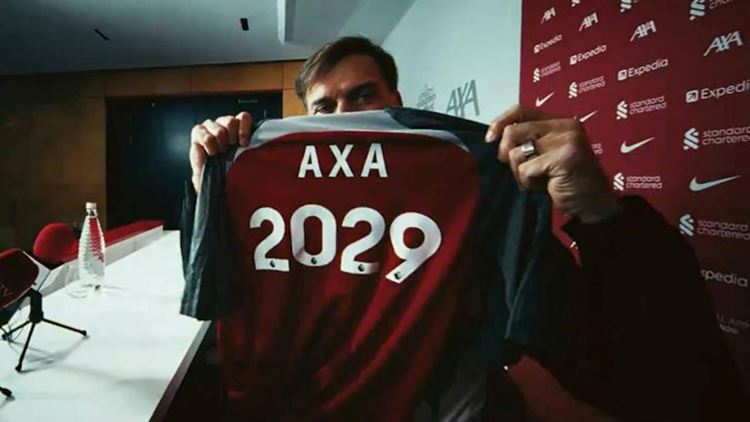 Man holding a Liverpool FC shirt with AXA 2029 printed on the reverse
