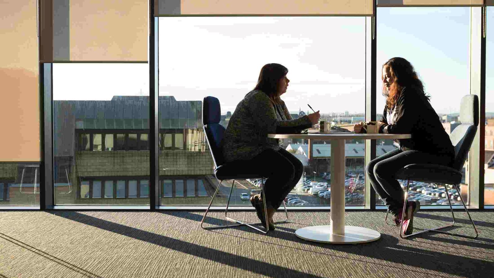 Two AXA employees sat at a table having a one-to-one meeting
