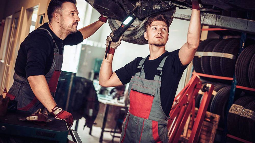 Mechanics inspecting underside of car