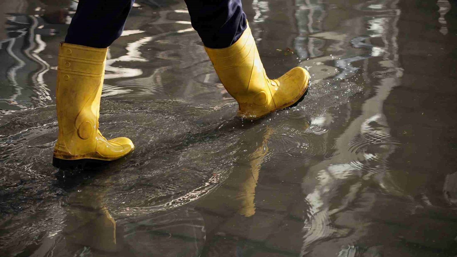 Walking in a flood masthead with a pair of yellow waterproof boot 