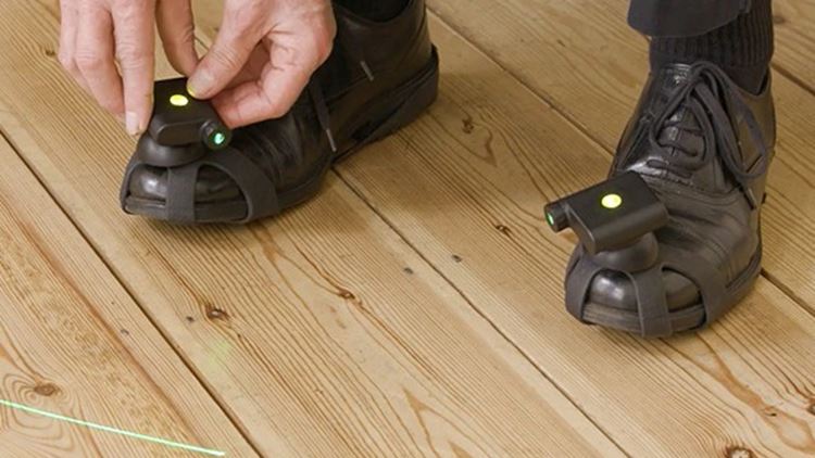 Man with Parinkson's wearing shoes with laser gadget attached for guidance