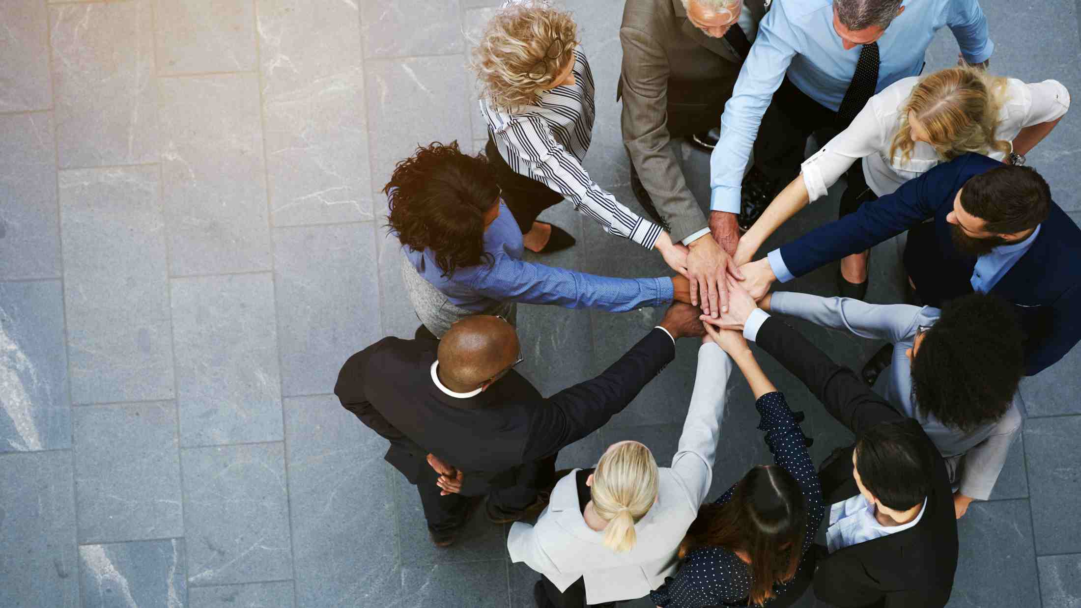 Close up top view of young business people putting their hands together