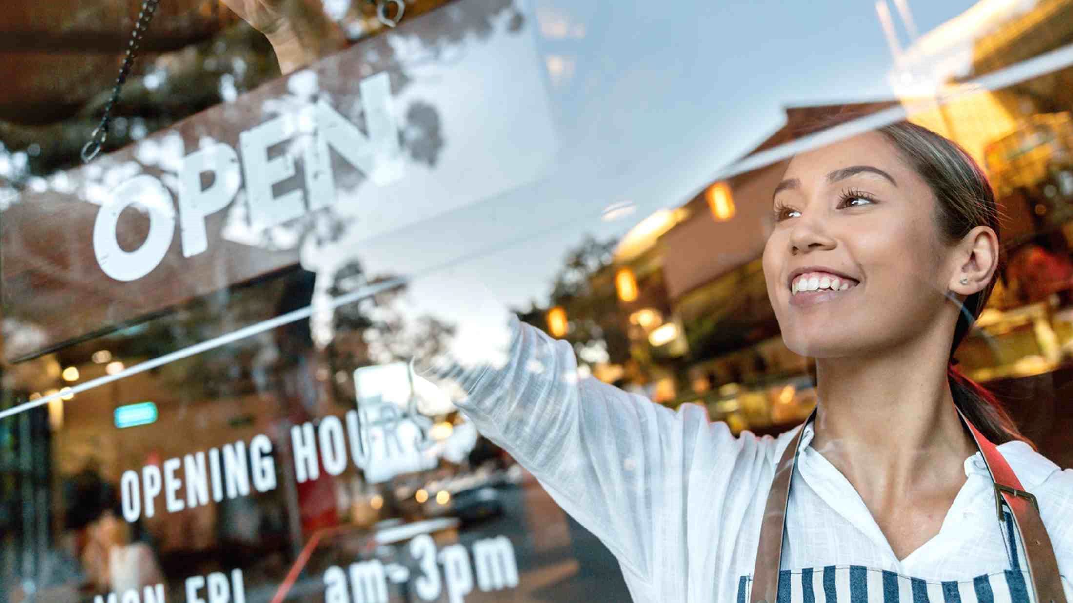 Photo of Woman Smiling While Holding Open Signage