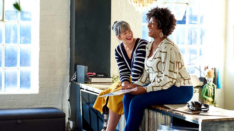 Mature women laughing together in stylish loft apartment