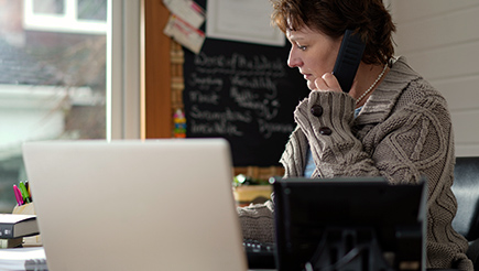 Wendy, late-40s woman with short brown hairsitting on the phone in an office.