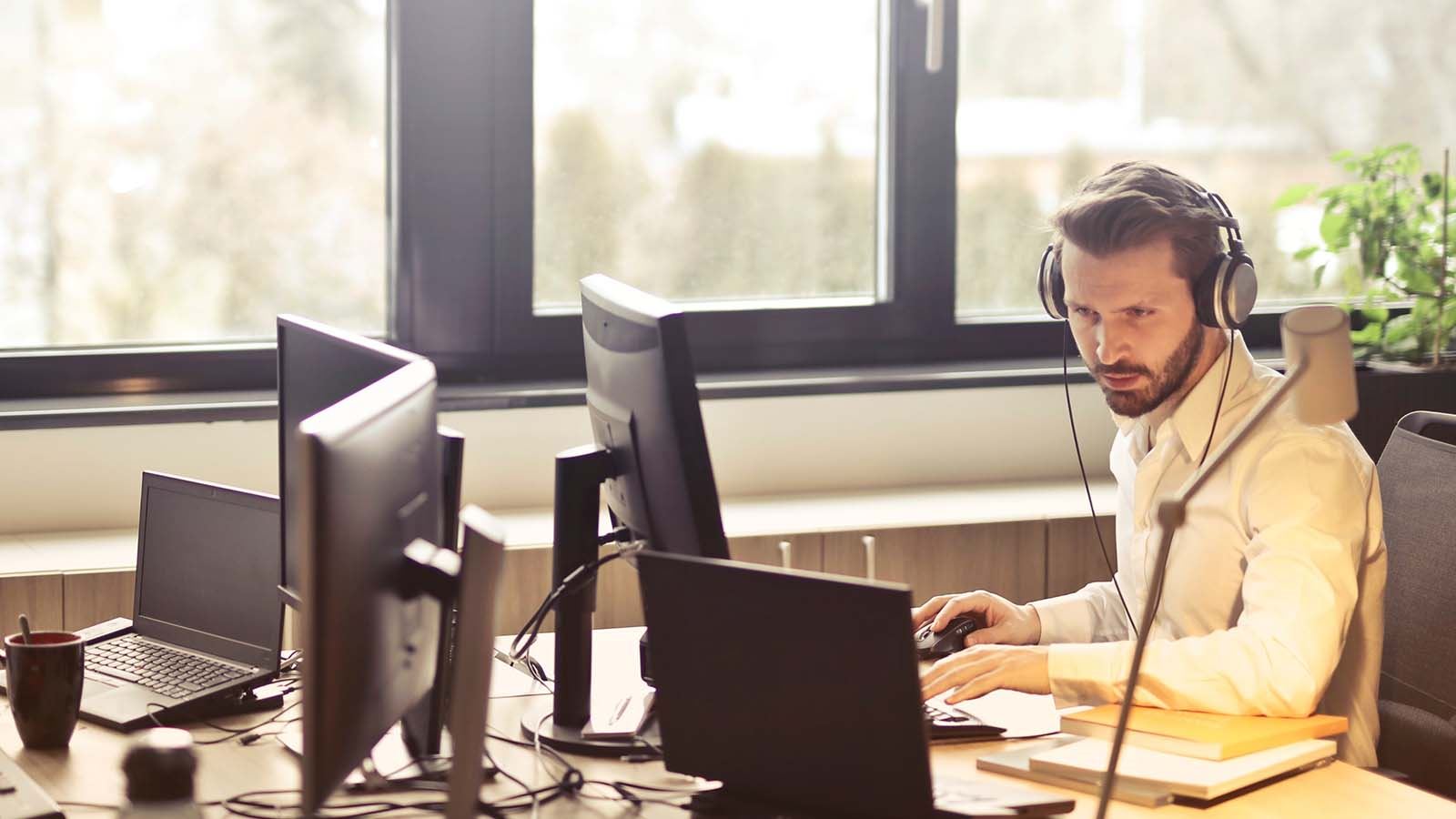 A man working with his headset and desktop in a office