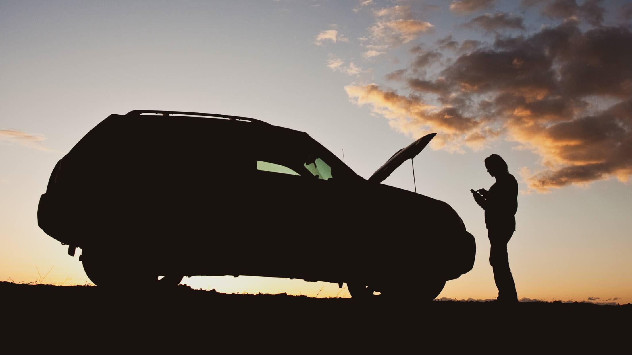Woman texting for help with car trouble beside road