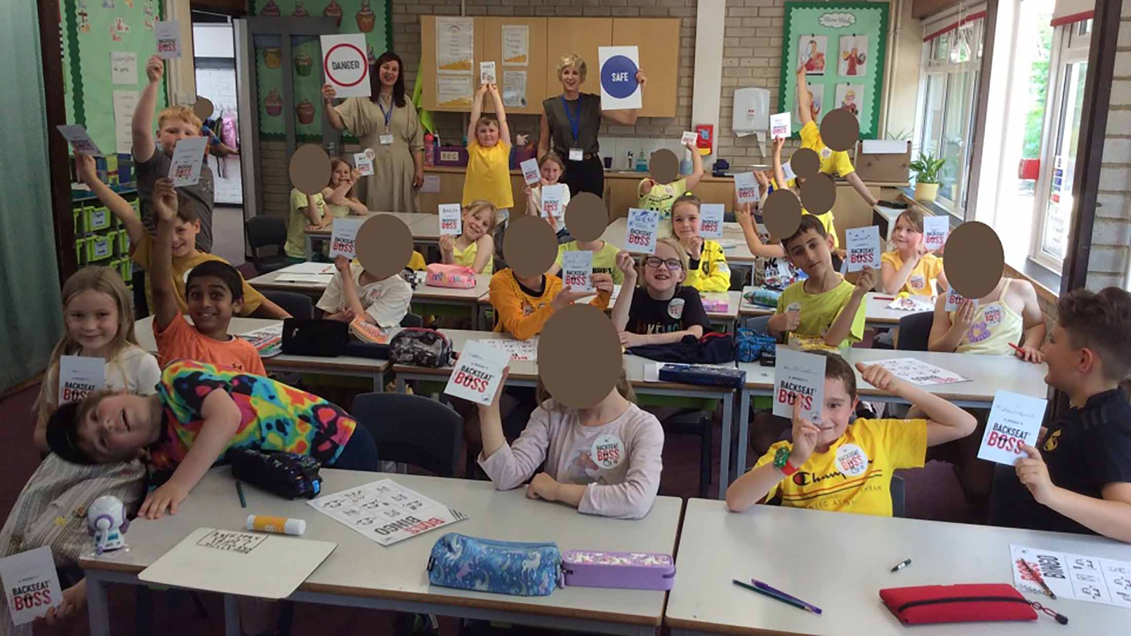 School children in classroom holding their AXA Backseat Boss information pack
