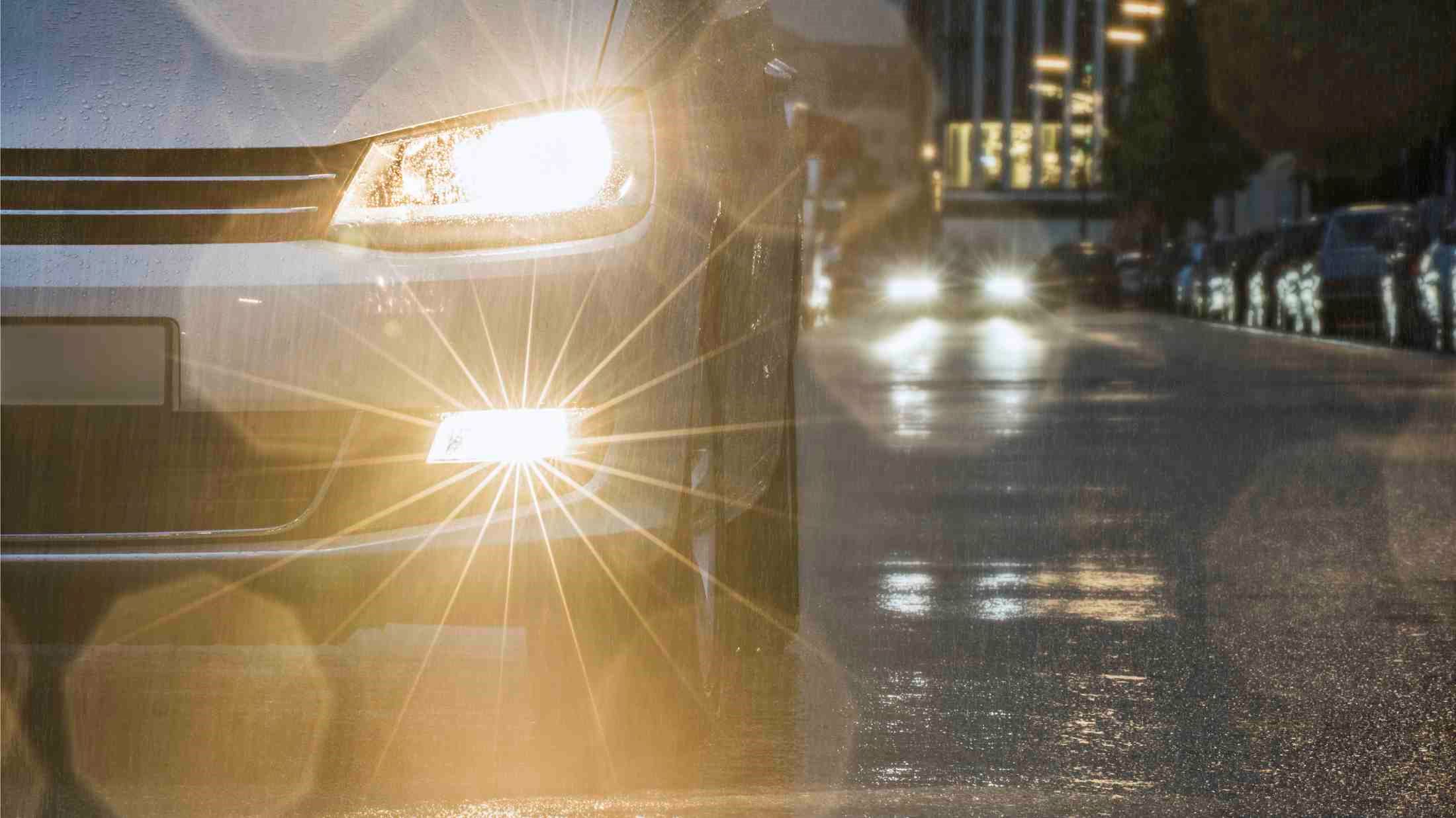 Car driving down urban street in rain