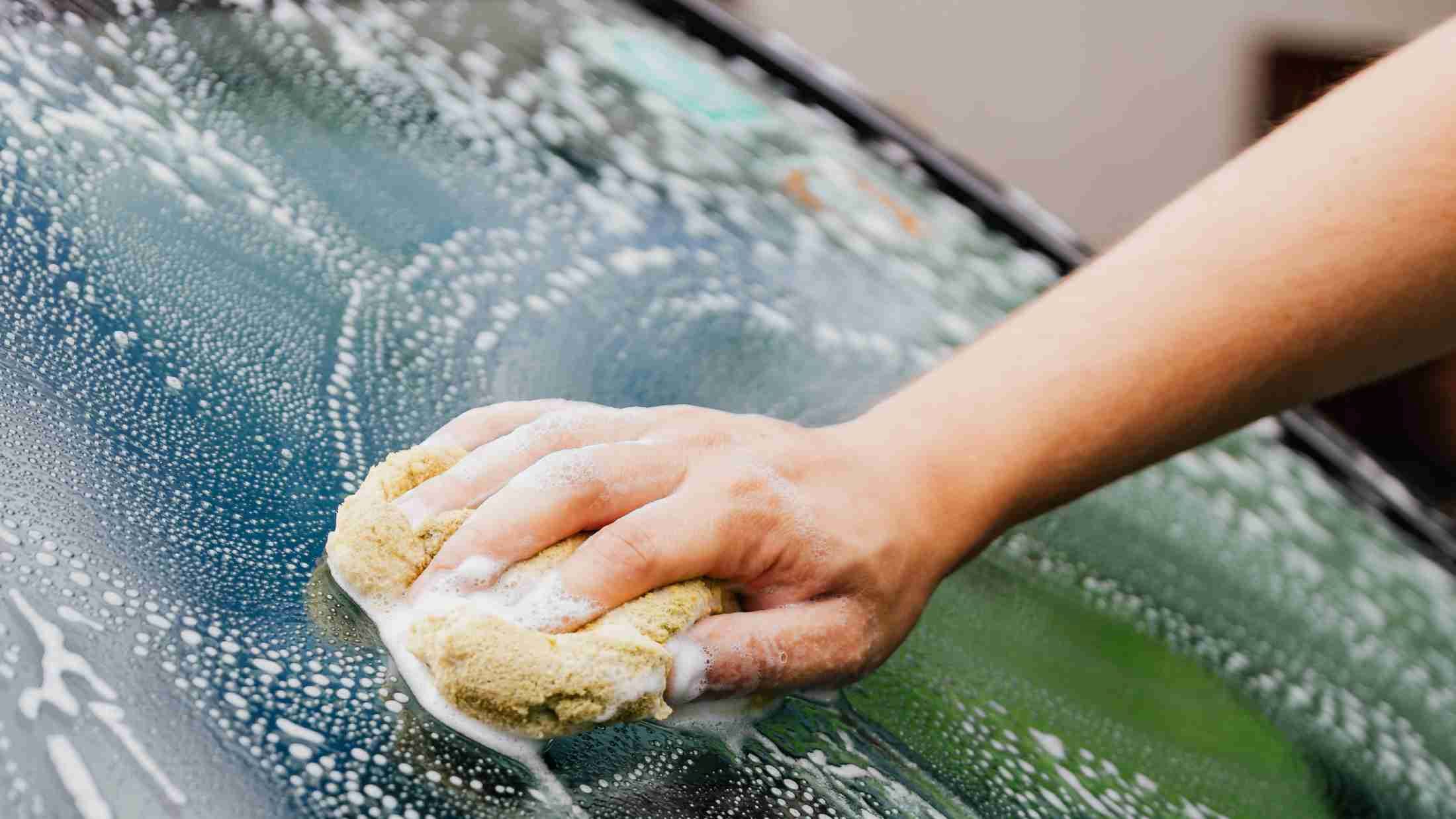 Cleaning a car window with soap and a sponge