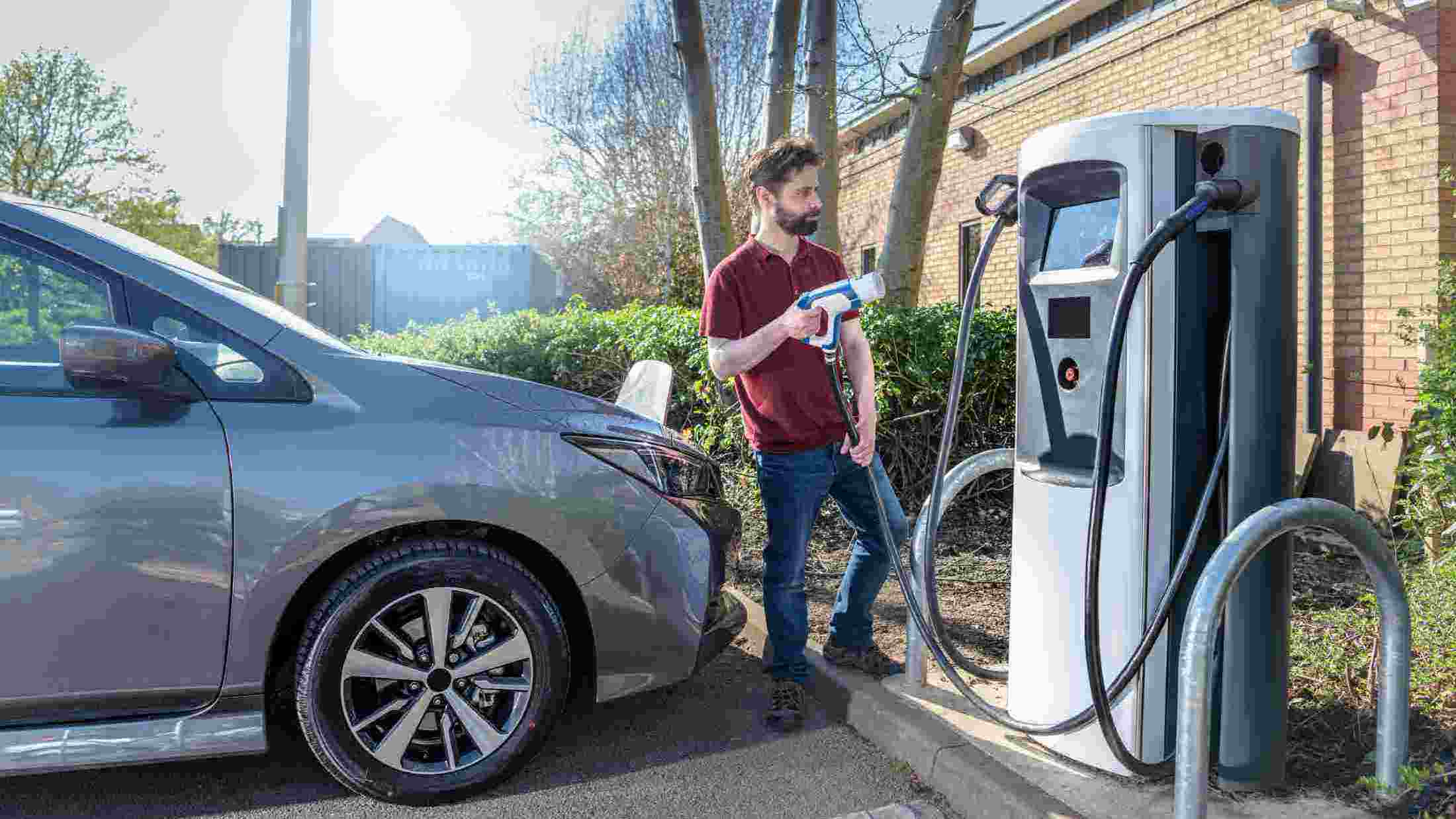 man charging electric car at car park charging point