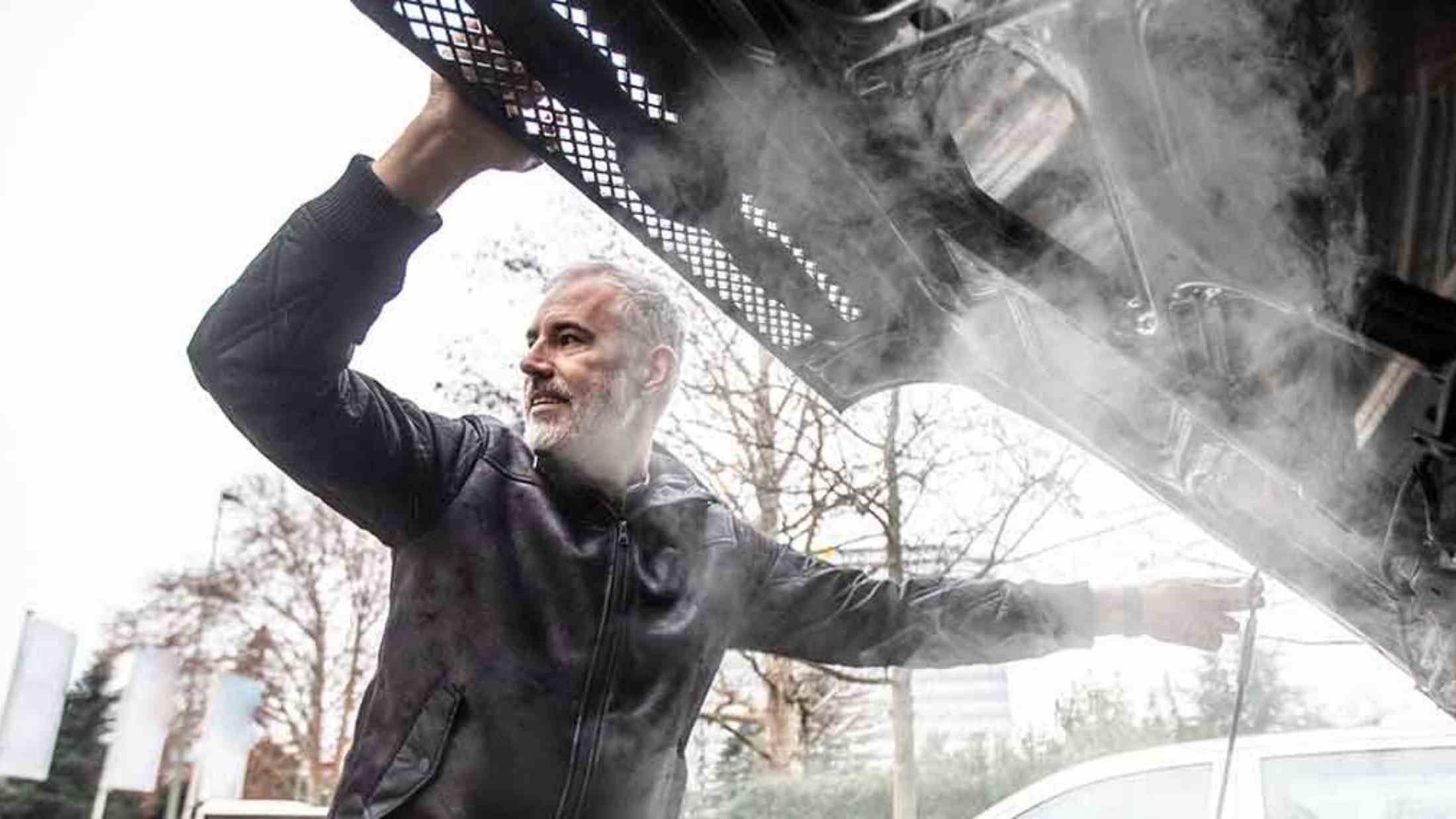 Man looking at overheated car engine