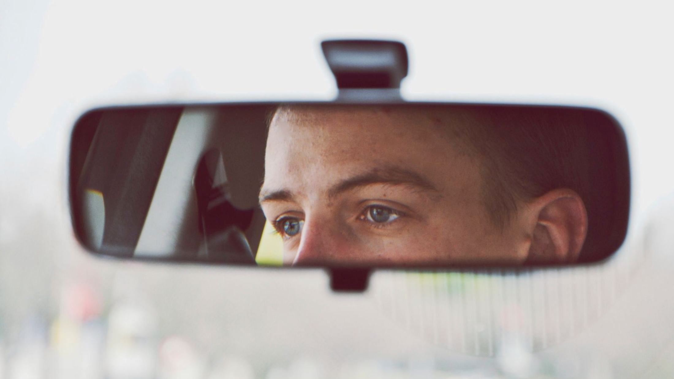 Reflection of man in car rear-view mirror
