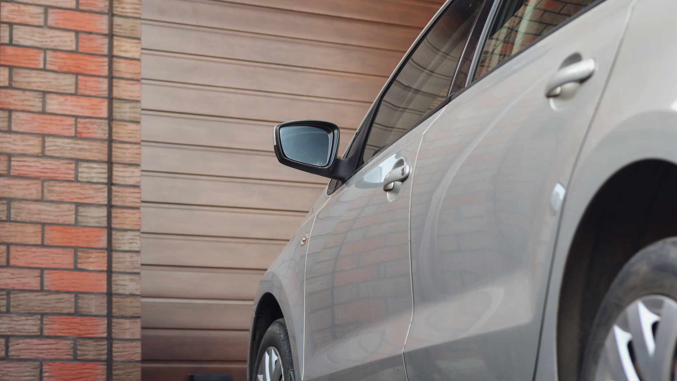 Silver car parked on driveway in front of garage with a brown door