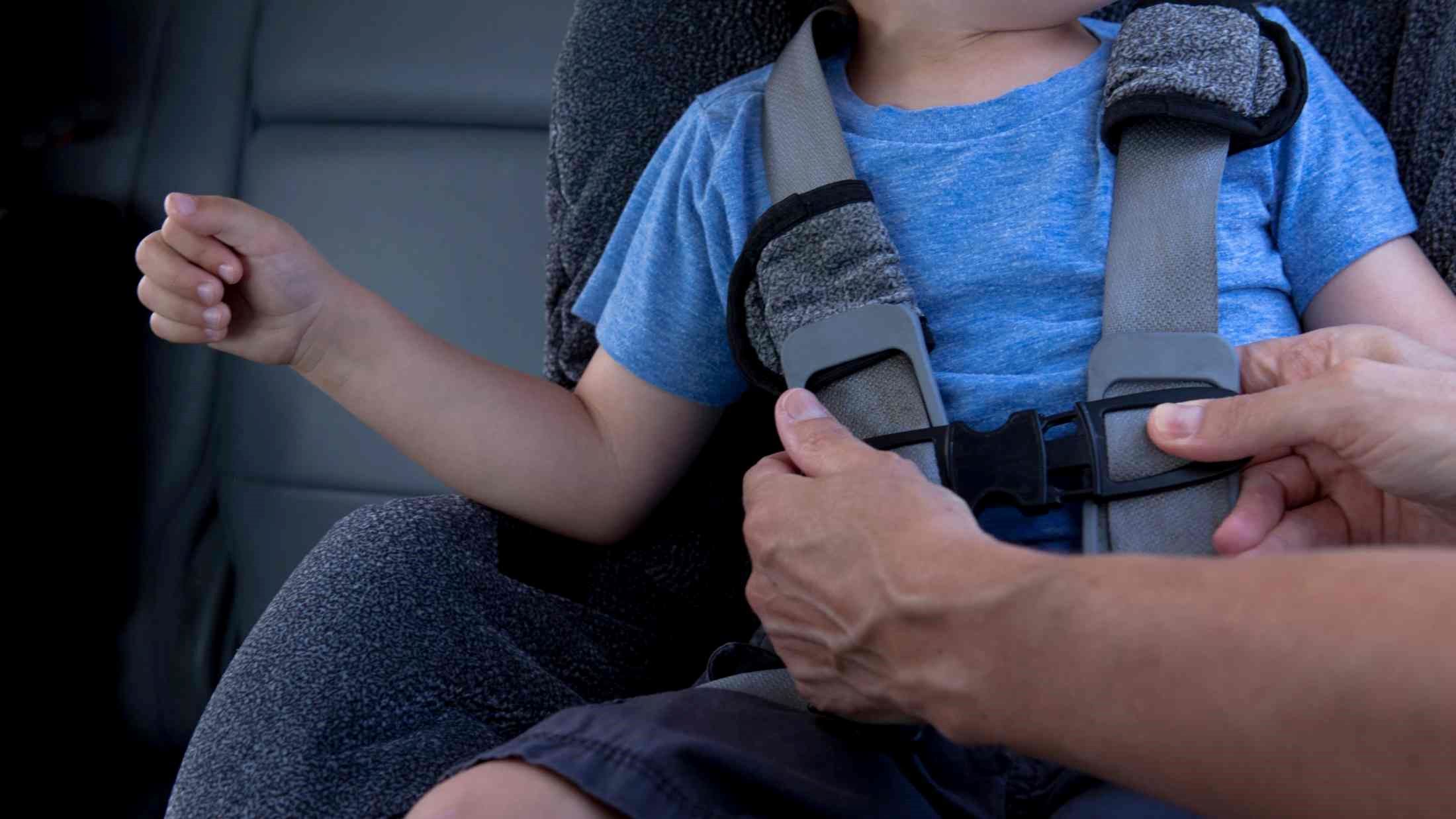 Toddler being strapped into his car seat