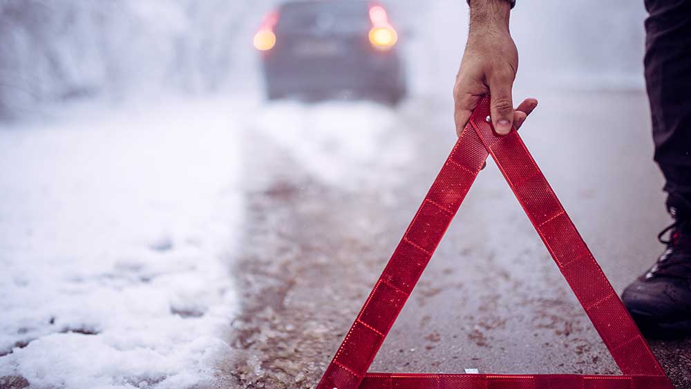 Triangle warning sign behind a car on winter road