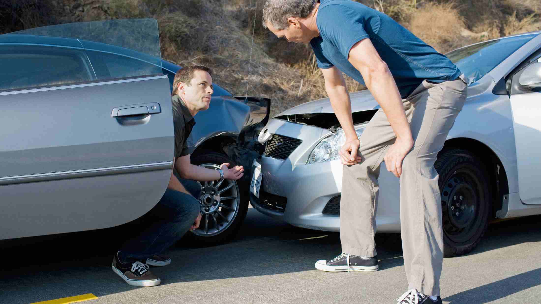 Two men examining damage in car collision