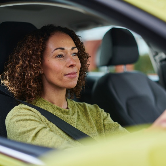 woman wearing a green jumper drviing a green car