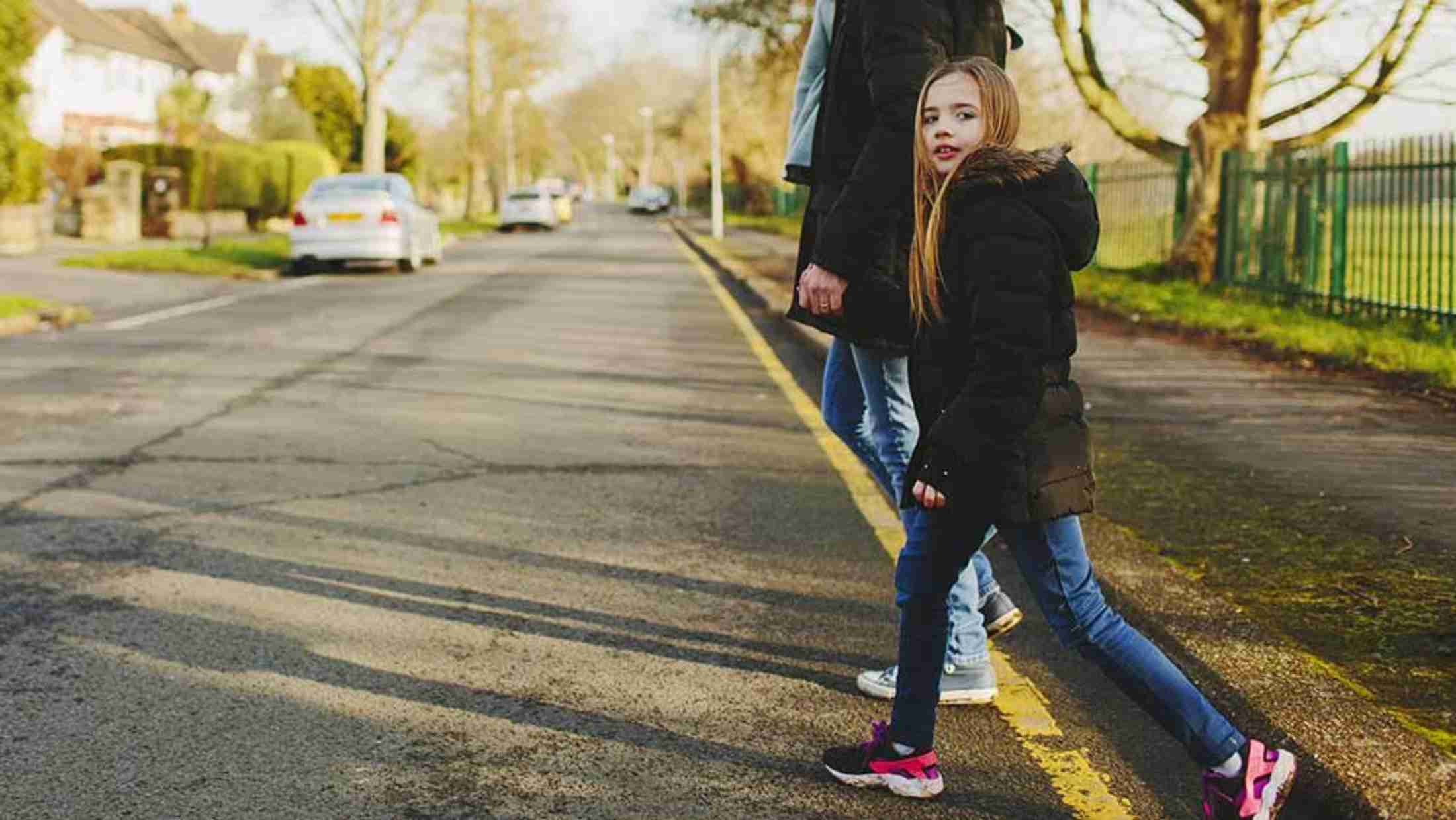 A parent and child crossing the road holding hands