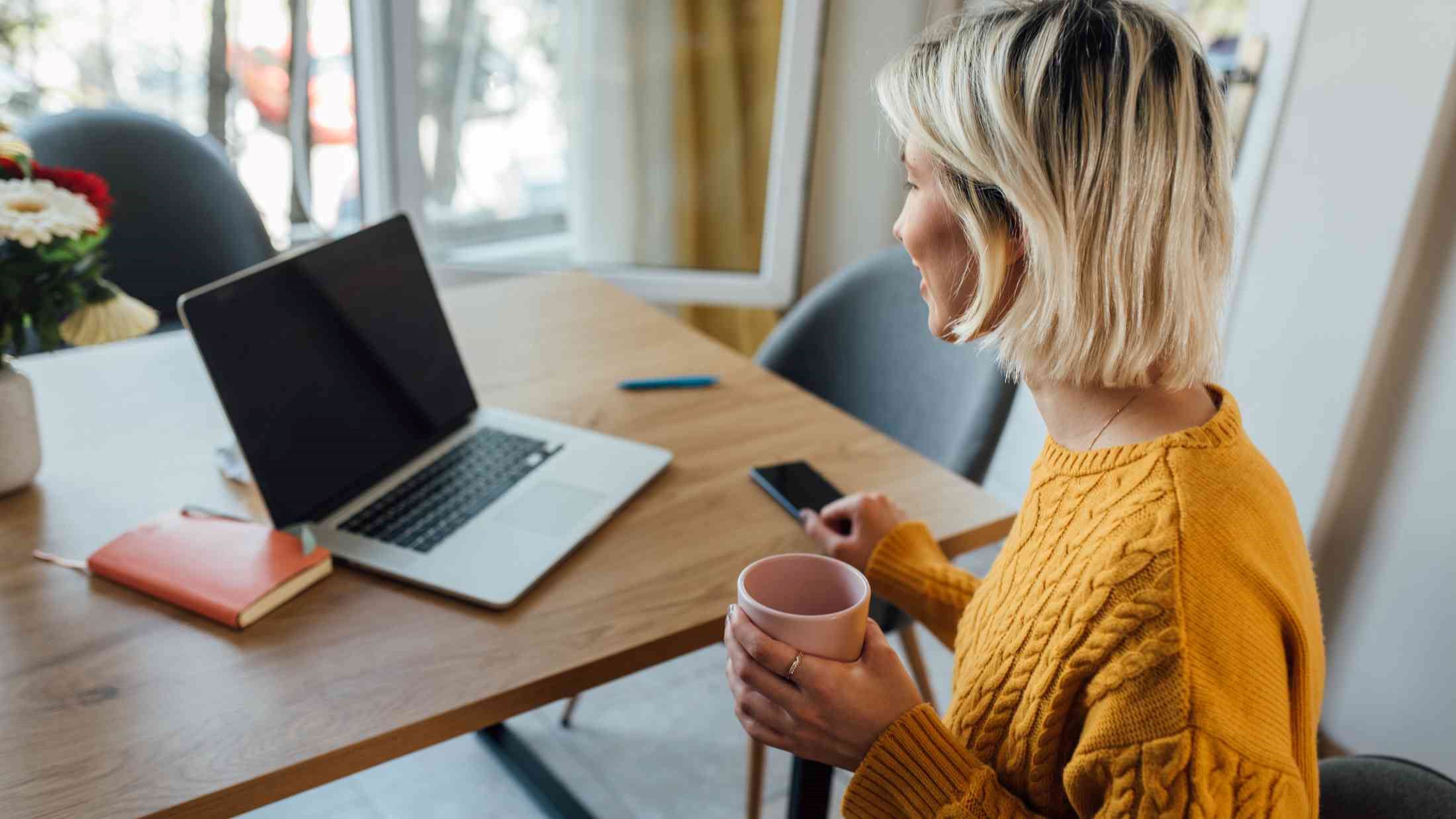 Young woman drinking morning coffee and starting her online work
