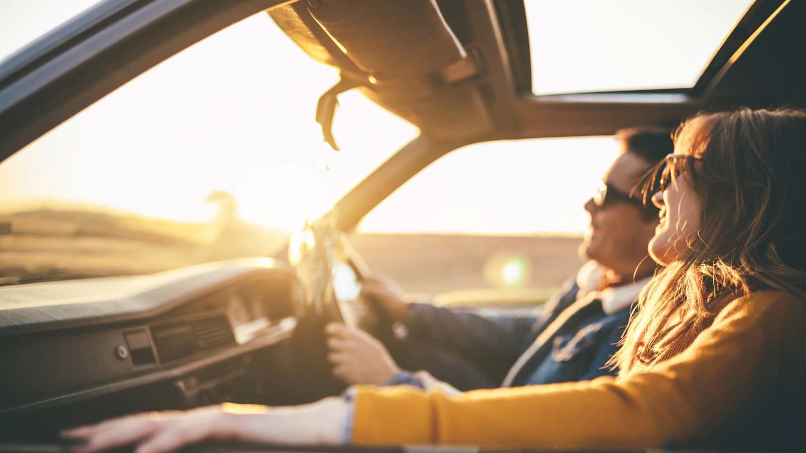 Couple in car on road trip enjoying sunset