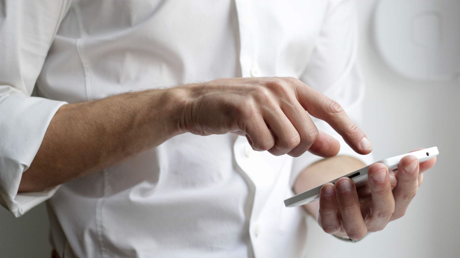 Man wearing white shirt holding white android phone