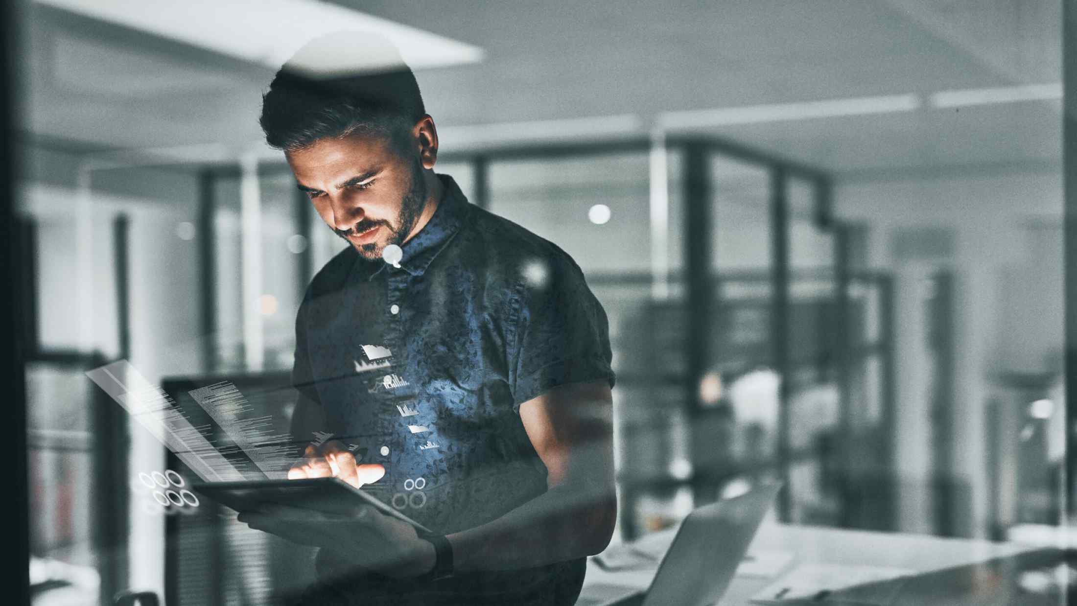 Man working on tablet in office with reflection in window