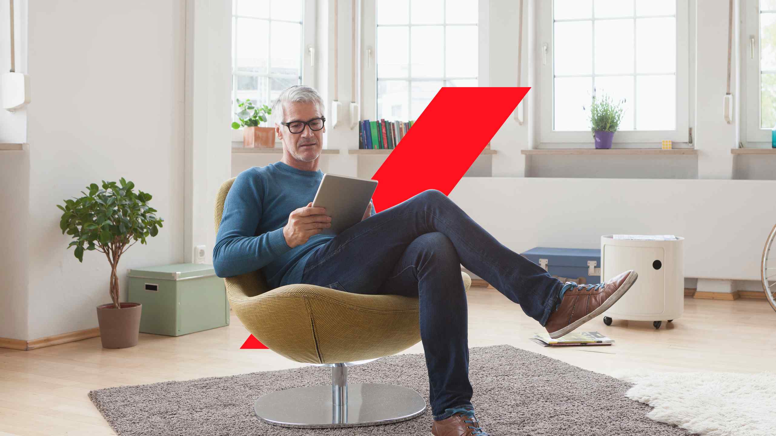 Mature man at home sitting in chair using digital tablet