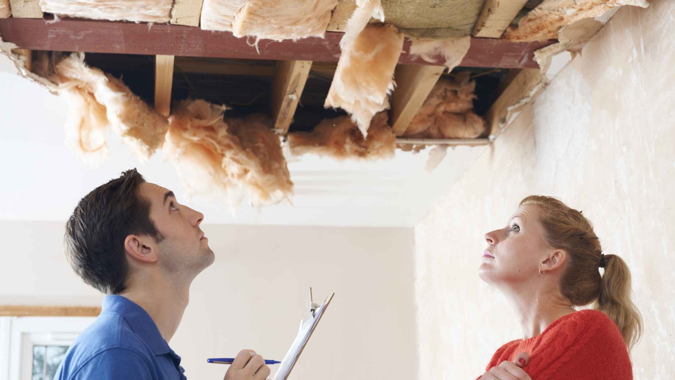 An inspector looks at a ceiling that's collapsed with a woman