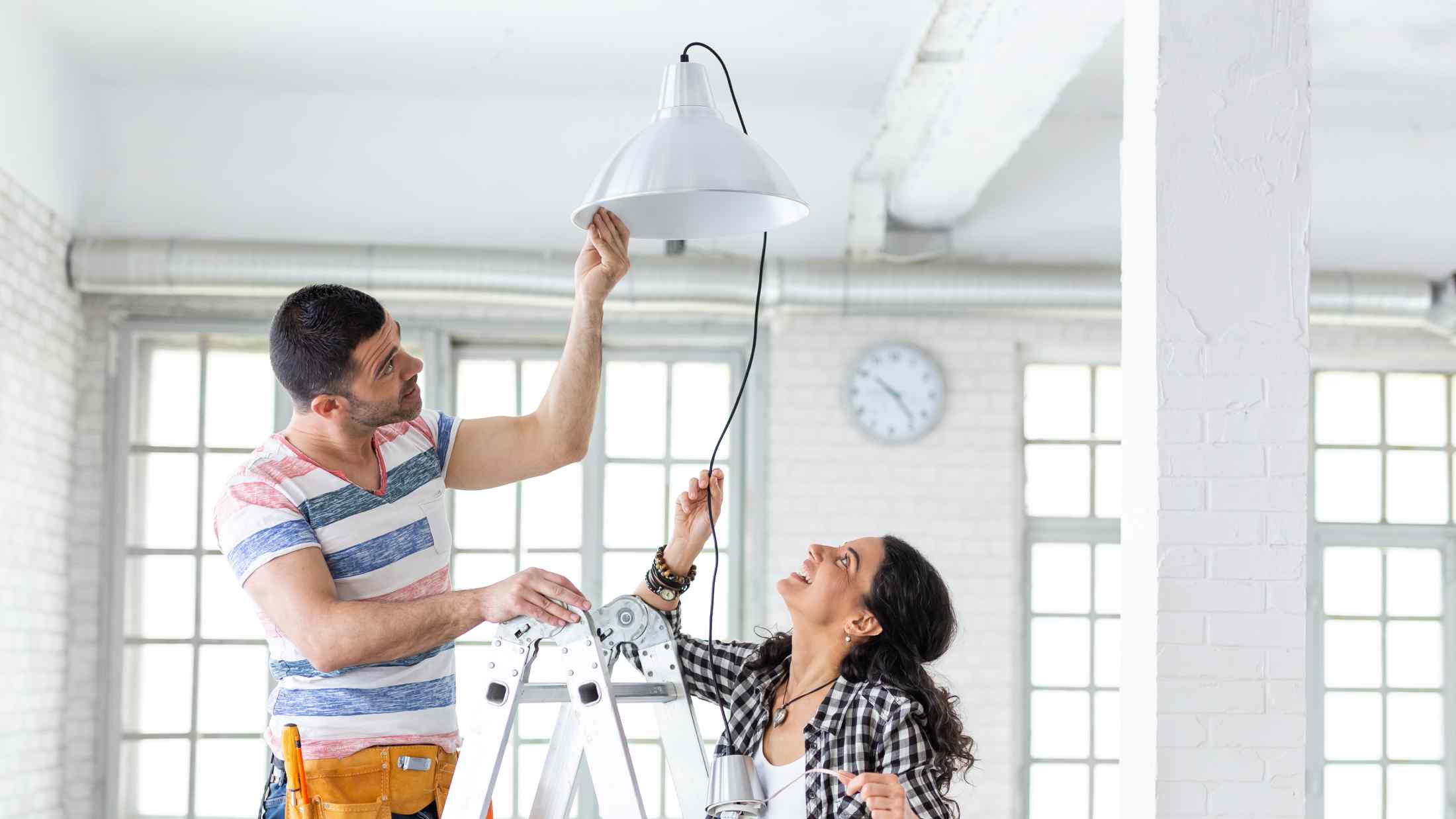 Couple hanging a lamp in new apartment